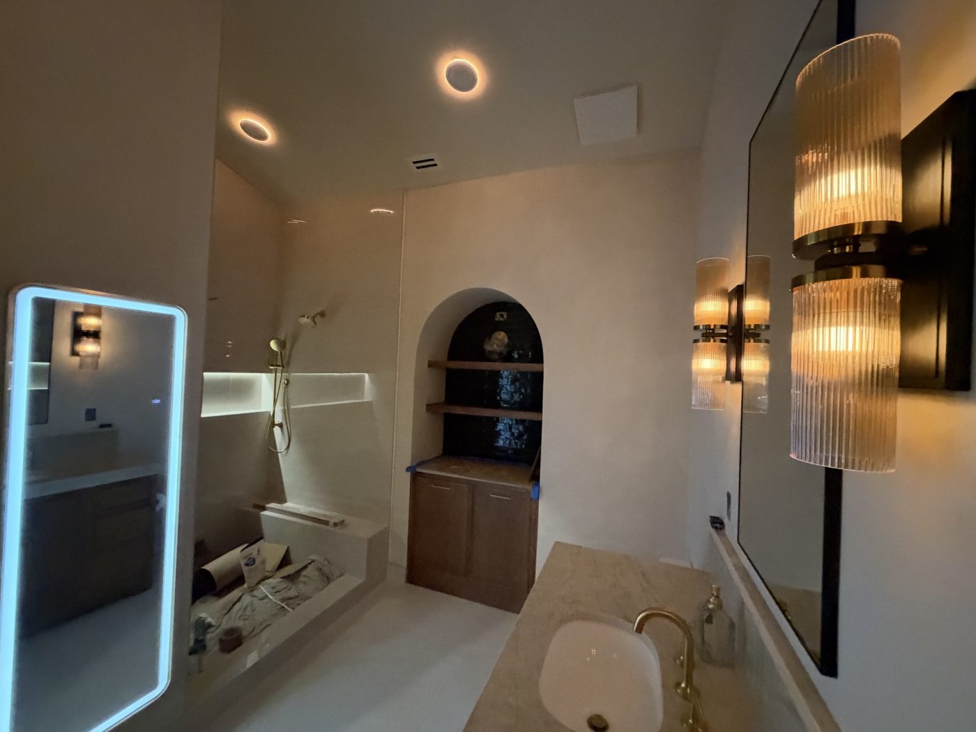 Custom bathroom remodel with arched niche and brass fixtures