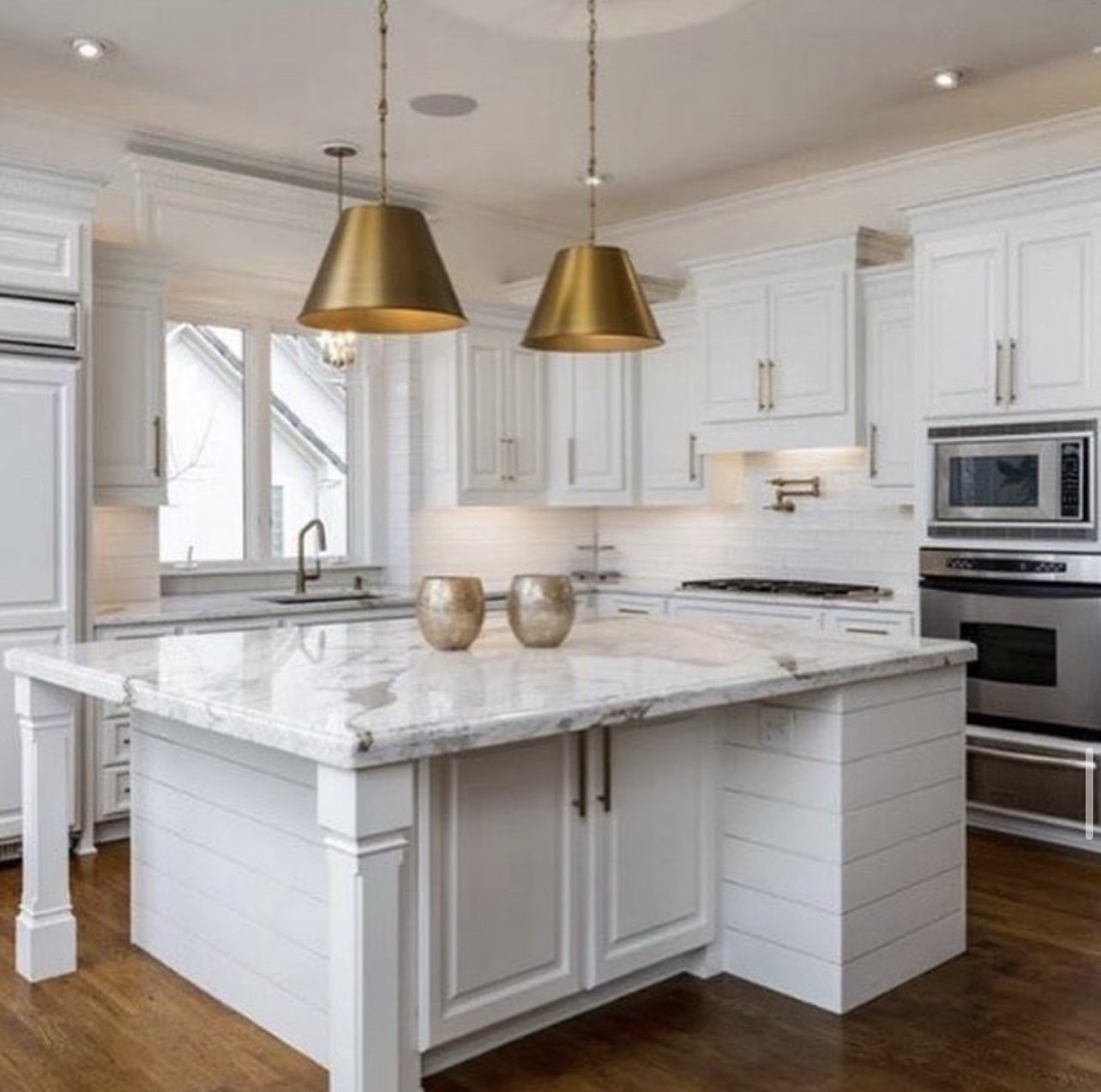White kitchen remodel with marble island and brass pendants
